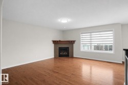 Hardwood flooring, fireplace with wood mantel, large window with blinds, and flush-mount ceiling light - 
