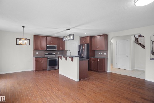 Kitchen featuring wood-finish cabinetry, stainless steel appliances, and dark countertops - 8432 18 Avenue Sw, Edmonton, AB - Indoor Photo Showing Kitchen