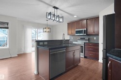 Kitchen featuring a central island with an integrated sink, dark cabinetry, and stainless steel appliances - 