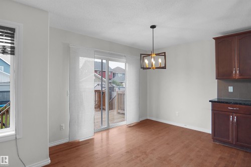 Wood-finish flooring, sliding glass door with panel blinds, contemporary ceiling fixture, built-in cabinetry with dark countertops - 8432 18 Avenue Sw, Edmonton, AB - Indoor