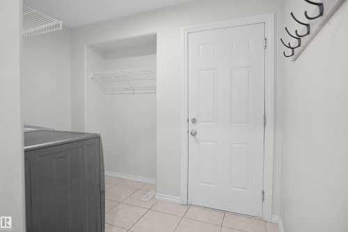 White paneled door with polished chrome hardware, durable tile flooring, and integrated wire shelving - 8432 18 Avenue Sw, Edmonton, AB - Indoor Photo Showing Other Room