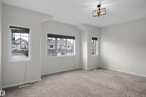 Neutral wall paint, light-colored carpet flooring, multiple windows, and a contemporary ceiling light fixture - 8432 18 Avenue Sw, Edmonton, AB - Indoor Photo Showing Other Room