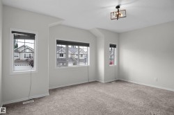 Neutral wall paint, light-colored carpet flooring, multiple windows, and a contemporary ceiling light fixture - 