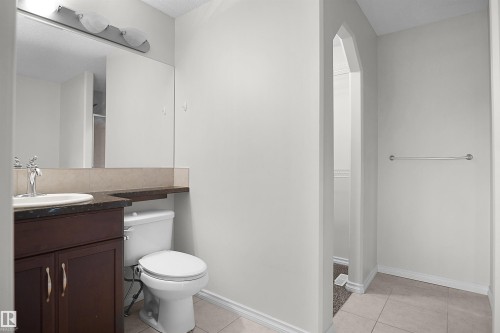 Dark wood-finish vanity with a single basin sink, dark stone-finish countertop, and full-width mirror - 8432 18 Avenue Sw, Edmonton, AB - Indoor Photo Showing Bathroom