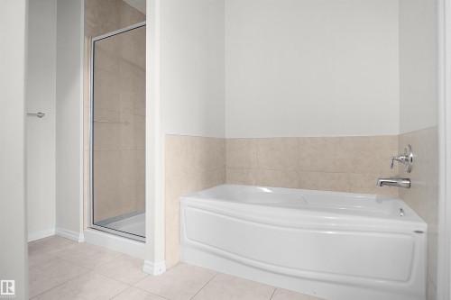 Built-in bathtub with chrome fixtures, tiled wainscoting, and large format tiled flooring - 8432 18 Avenue Sw, Edmonton, AB - Indoor Photo Showing Bathroom