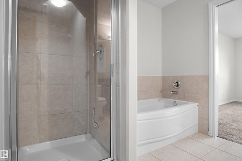 Glass-enclosed shower with tiled walls and a built-in light fixture - 8432 18 Avenue Sw, Edmonton, AB - Indoor Photo Showing Bathroom