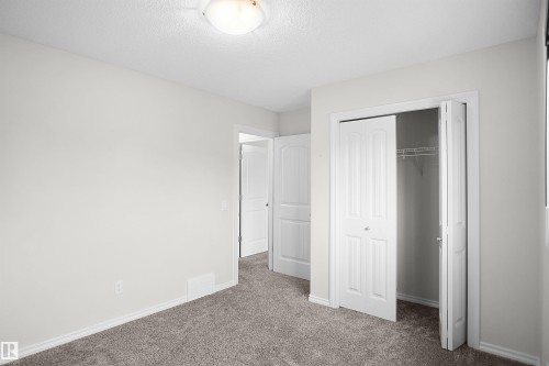 Plush gray carpeting, neutral wall palette, white trim, and bi-fold closet doors with wire shelving - 8432 18 Avenue Sw, Edmonton, AB - Indoor