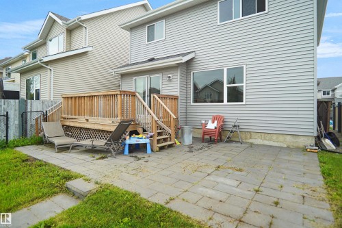 Rear exterior featuring light grey siding, a wood deck with stairs, a sliding glass door, and a paver patio - 8432 18 Avenue Sw, Edmonton, AB - Outdoor With Deck Patio Veranda With Exterior