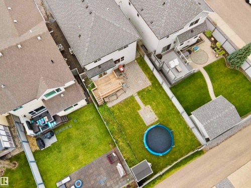 Aerial view showcasing a well-appointed residential property featuring manicured lawn, circular in-ground trampoline, multiple outbuildings with modern architectural design, and organized hardscaping throughout the expansive grounds - 8432 18 Avenue Sw, Edmonton, AB - Outdoor With View