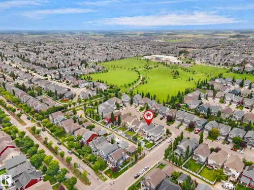 Aerial perspective of a residential neighborhood featuring diverse architectural styles, mature trees, and a large green space with a building - 8432 18 Avenue Sw, Edmonton, AB - Outdoor With View