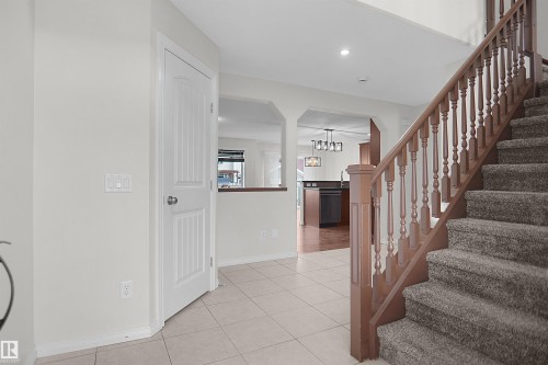 Ceramic tile flooring, carpeted staircase, wood banister with turned spindles, paneled interior door, recessed lighting - 8432 18 Avenue Sw, Edmonton, AB - Indoor Photo Showing Other Room