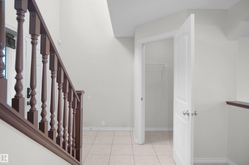 Tiled flooring with contrasting baseboards, painted walls, and a wooden stair railing - 8432 18 Avenue Sw, Edmonton, AB - Indoor Photo Showing Other Room