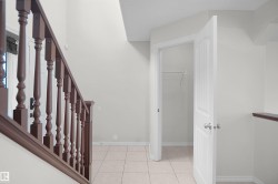 Tiled flooring with contrasting baseboards, painted walls, and a wooden stair railing - 