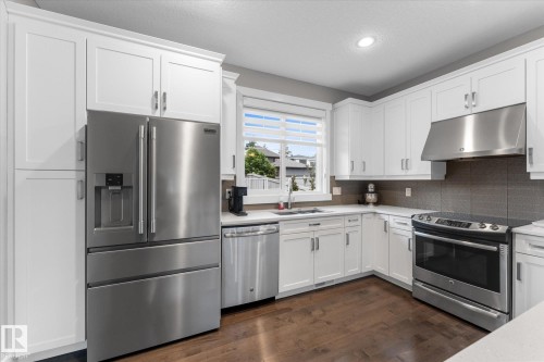 Kitchen with white cabinetry, stainless steel appliances, wood-finish flooring, and light-toned countertops - 5616 Juchli Avenue Nw, Edmonton, AB - Indoor Photo Showing Kitchen
