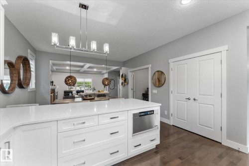 Kitchen island with white cabinetry, stainless steel microwave drawer, and a light-toned countertop - 5616 Juchli Avenue Nw, Edmonton, AB - Indoor