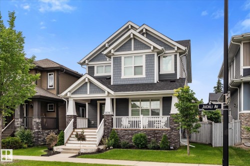 Two-story residence featuring a covered front porch, stone and siding exterior, multi-pane windows, and a landscaped front yard - 5616 Juchli Avenue Nw, Edmonton, AB - Outdoor With Deck Patio Veranda With Facade
