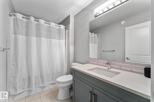 Modern bathroom featuring a gray vanity with an undermount sink, white quartz countertop, subway tile backsplash, and chrome fixtures - 5616 Juchli Avenue Nw, Edmonton, AB - Indoor Photo Showing Bathroom