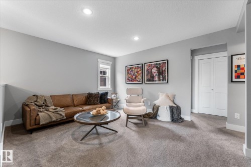 Recessed lighting illumination, neutral wall color, window with white trim, white paneled bifold doors, and gray carpeting - 5616 Juchli Avenue Nw, Edmonton, AB - Indoor Photo Showing Living Room