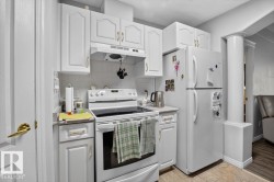 White cabinetry with gold-tone hardware, white range, white refrigerator, and tiled flooring - 