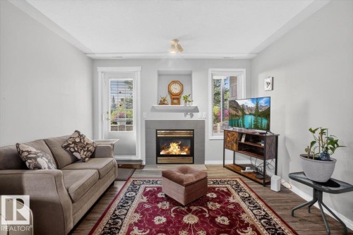 Fireplace with a mantel, two windows, and wood-finish flooring - #116 237 Youville Dr E Nw, Edmonton, AB - Indoor Photo Showing Living Room With Fireplace