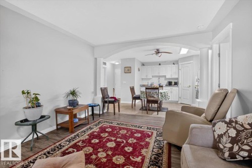Open-concept living area with wood-finish flooring, recessed lighting, and crown molding - #116 237 Youville Dr E Nw, Edmonton, AB - Indoor Photo Showing Living Room