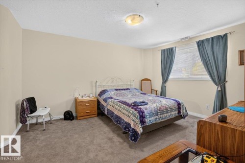 Neutral-toned walls complement the textured ceiling - #116 237 Youville Dr E Nw, Edmonton, AB - Indoor Photo Showing Bedroom