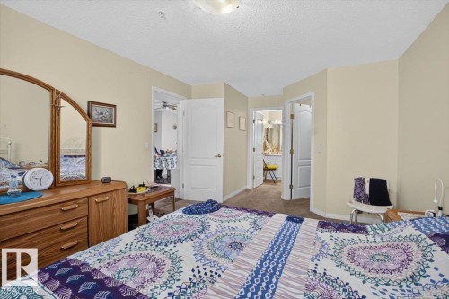 Carpeted flooring, neutral wall color, and interior doors with curved arch details - #116 237 Youville Dr E Nw, Edmonton, AB - Indoor Photo Showing Bedroom