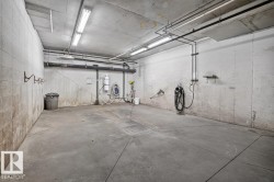 Concrete flooring with a central drainage system, exposed overhead piping, and fluorescent lighting - 