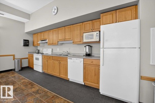 Full kitchen with wood cabinetry, gray countertops, and tile flooring - #116 237 Youville Dr E Nw, Edmonton, AB - Indoor Photo Showing Kitchen