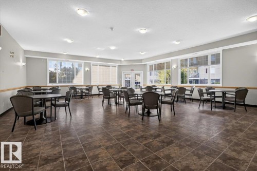 Spacious room featuring multiple large windows, recessed ceiling lights, sconce lighting, and durable tile flooring - #116 237 Youville Dr E Nw, Edmonton, AB - Indoor Photo Showing Dining Room
