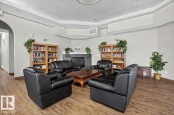Spacious common area featuring wood-finish flooring, built-in bookshelves, a corner fireplace, and crown molding - 