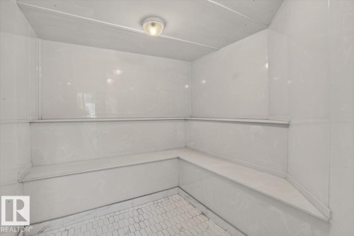 Built-in bench seating with a white finish, white wall paneling, and a floor featuring white hexagonal tile - #116 237 Youville Dr E Nw, Edmonton, AB - Indoor