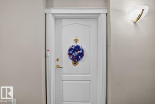 White paneled door with gold-toned hardware and a decorative door knocker - #116 237 Youville Dr E Nw, Edmonton, AB - Indoor Photo Showing Other Room