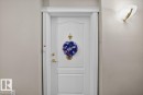 White paneled door with gold-toned hardware and a decorative door knocker - #116 237 Youville Dr E Nw, Edmonton, AB  - Indoor Photo Showing Other Room 