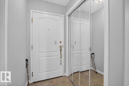 Entryway featuring a paneled door, mirrored closet doors, and tile flooring - #116 237 Youville Dr E Nw, Edmonton, AB - Indoor Photo Showing Other Room