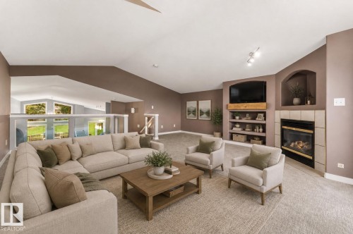 Spacious living area featuring a corner fireplace with tile surround, built-in shelving, vaulted ceilings, and a glass-paneled railing - 8 Osborne Close, St. Albert, AB - Indoor Photo Showing Living Room With Fireplace