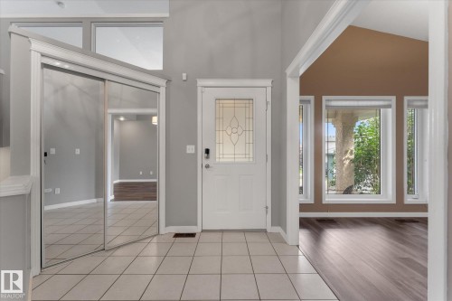 Tiled entryway with a decorative glass front door, mirrored closet doors, and transom windows - 8 Osborne Close, St. Albert, AB - Indoor Photo Showing Other Room