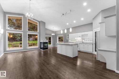 Vaulted ceiling with a contemporary chandelier, wood-finish flooring, floor-to-ceiling windows, and a built-in fireplace - 8 Osborne Close, St. Albert, AB - Indoor