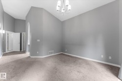 Vaulted ceiling with an arched entryway, recessed wall sconces, and a multi-arm chandelier - 