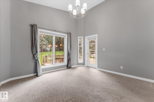 Vaulted ceilings with a chandelier, carpet flooring, a large window, a glass-paned door, and white trim - 8 Osborne Close, St. Albert, AB - Indoor Photo Showing Other Room