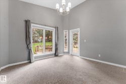 Vaulted ceilings with a chandelier, carpet flooring, a large window, a glass-paned door, and white trim - 