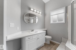 White vanity with a single basin sink, light-colored countertop, and oval mirror - 