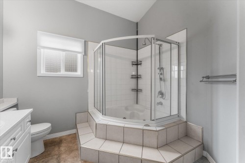 Corner shower with glass enclosure, white tile surround, and built-in shelving - 8 Osborne Close, St. Albert, AB - Indoor Photo Showing Bathroom