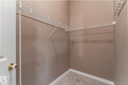 Corner walk-in closet featuring white wire shelving and a wall-mounted coat rack - 