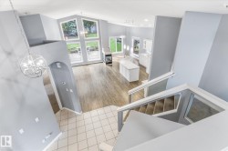 Vaulted ceilings, a contemporary chandelier, and large windows illuminate the main living area with wood-finish flooring - 