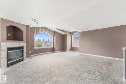 Built-in gas fireplace with tile surround, arched wall niche, vaulted ceilings, track lighting, and architectural windows - 