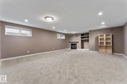 Spacious room featuring neutral carpeting, a built-in fireplace with mantel, recessed lighting, and windows providing natural light - 