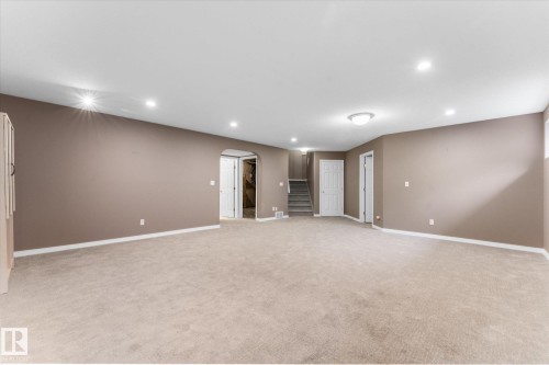 Expansive carpeted area with recessed lighting, neutral wall tones, and a built-in storage cabinet - 8 Osborne Close, St. Albert, AB - Indoor