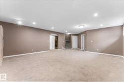 Expansive carpeted area with recessed lighting, neutral wall tones, and a built-in storage cabinet - 