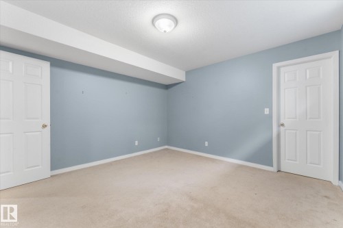 Carpeted room with light blue walls, two paneled doors, and a ceiling-mounted light fixture - 8 Osborne Close, St. Albert, AB - Indoor Photo Showing Other Room